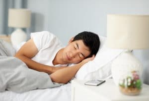 Cropped shot of a handsome young man sleeping under a duvet in his bed in the morning