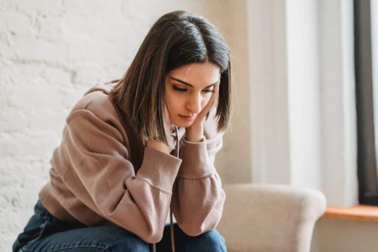 Tired looking younger woman sitting on couch.