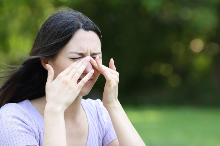 Woman rubbing top of nose with her hands.