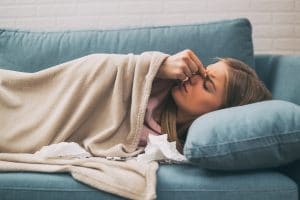 Woman with a cold lying down on a couch.
